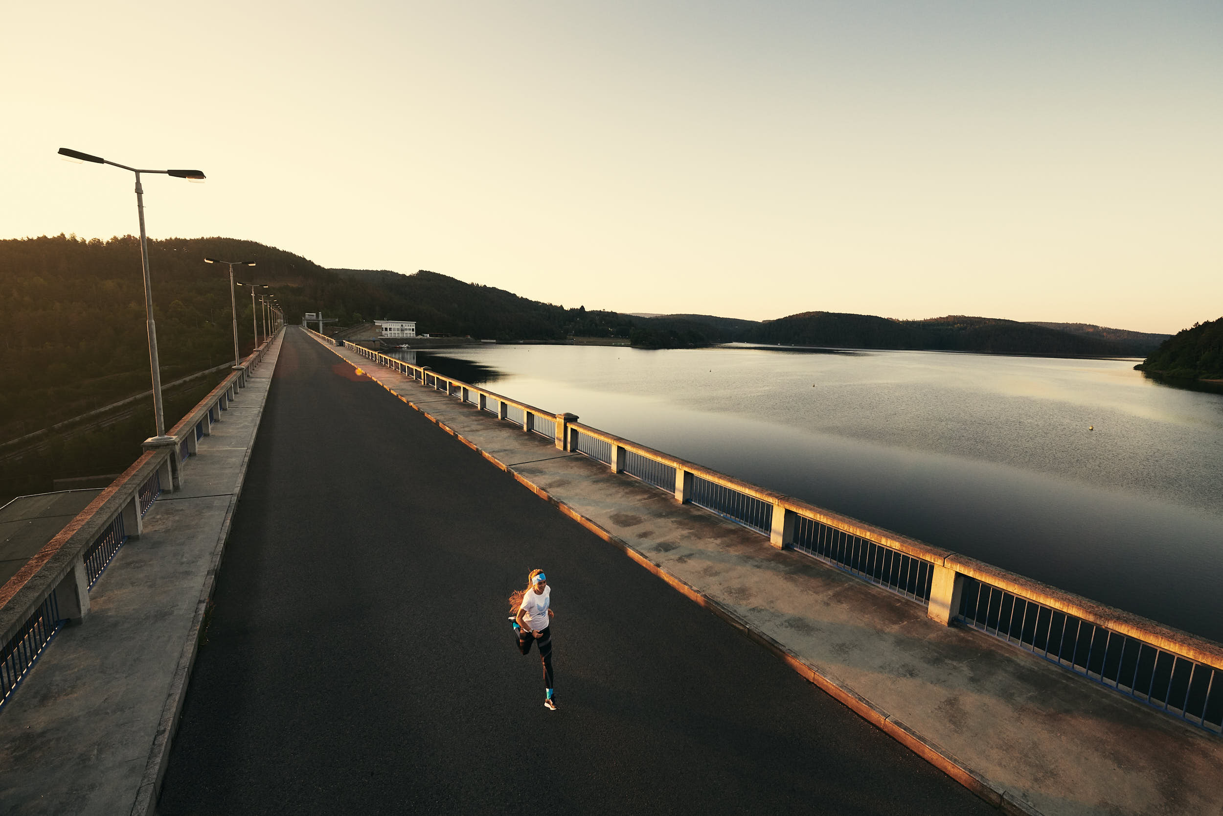 Sport advertising photography: girl running across a bridge in beautiful morning light.