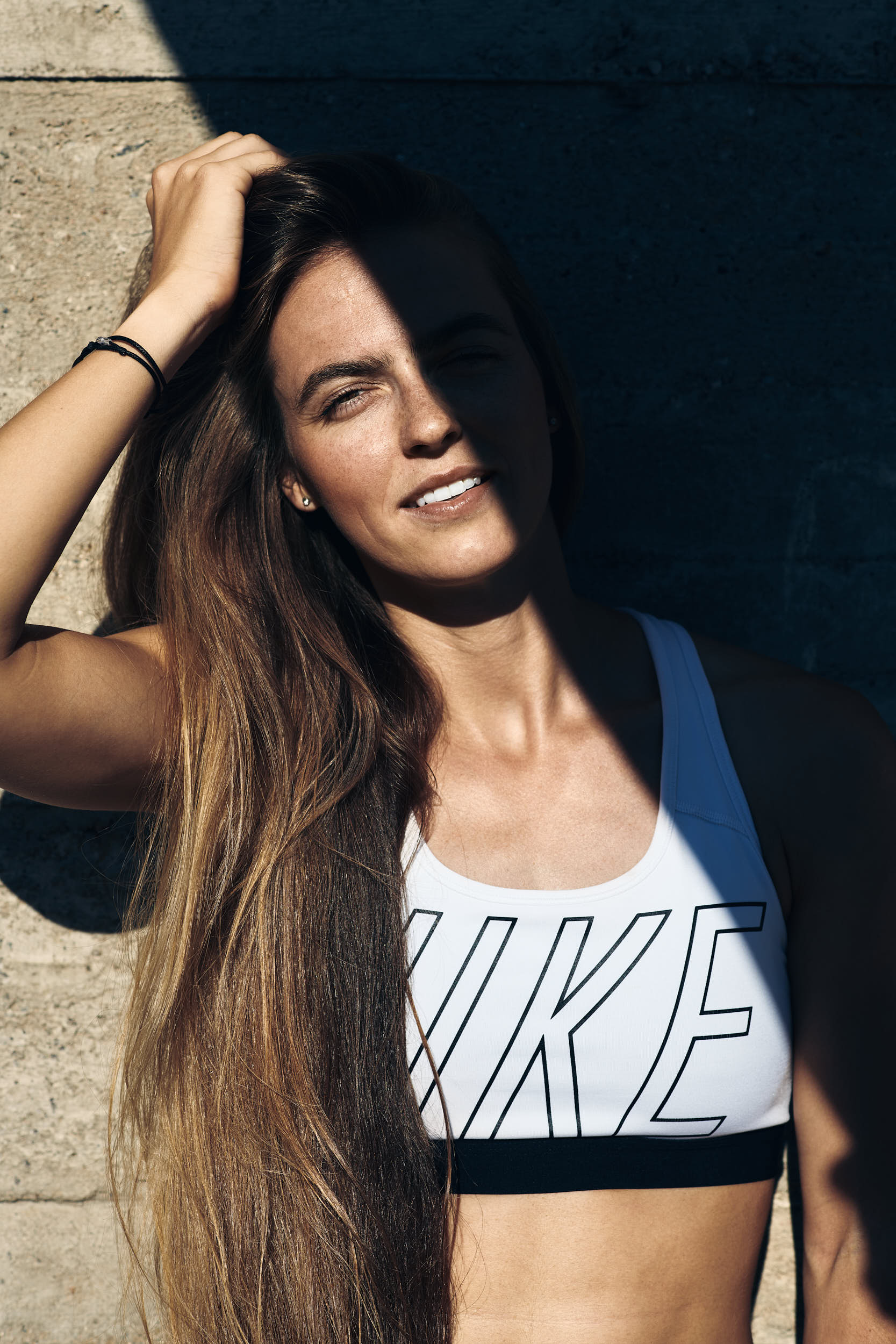 Active lifestyle photography: portrait of a girl posing in running apparel against a concrete wall.