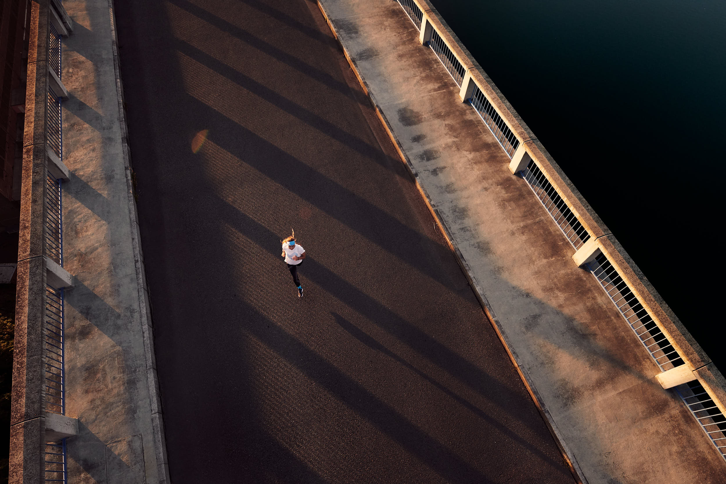 Sport advertising photography: girl running across a bridge in beautiful morning light.