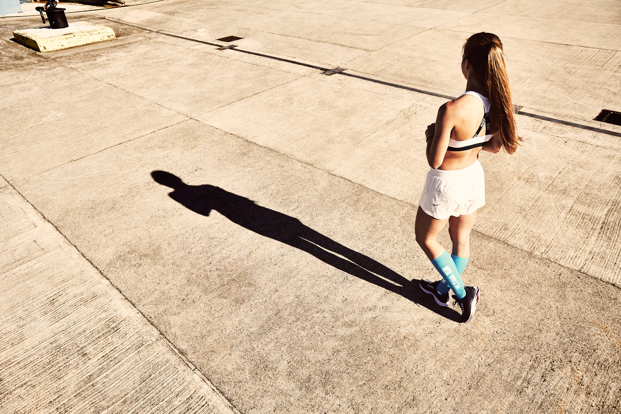 Girl posing in running apparel. Photograph with strong contrast and long shadows.