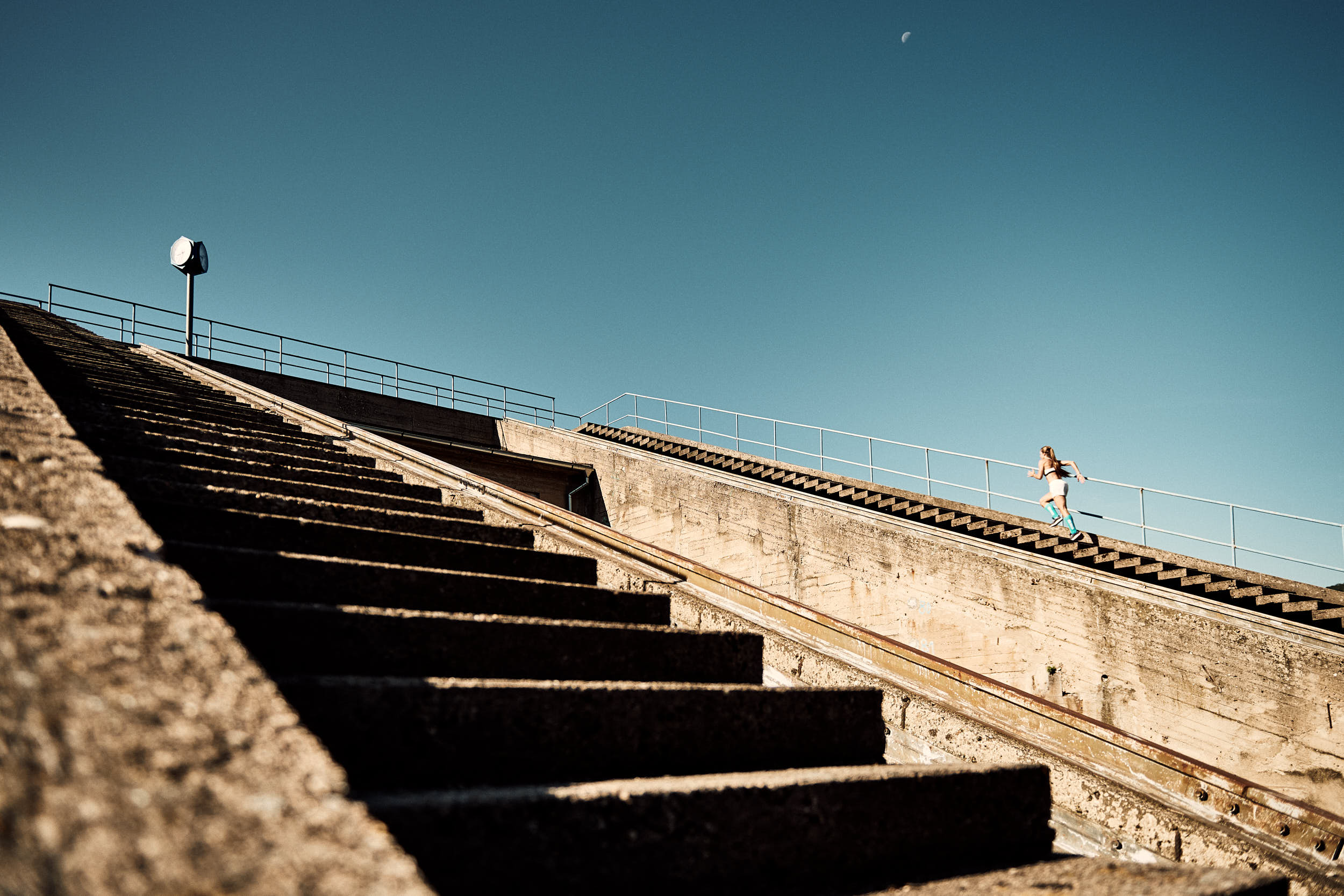 Action photography of a girl running up the stairs of a concrete structure.