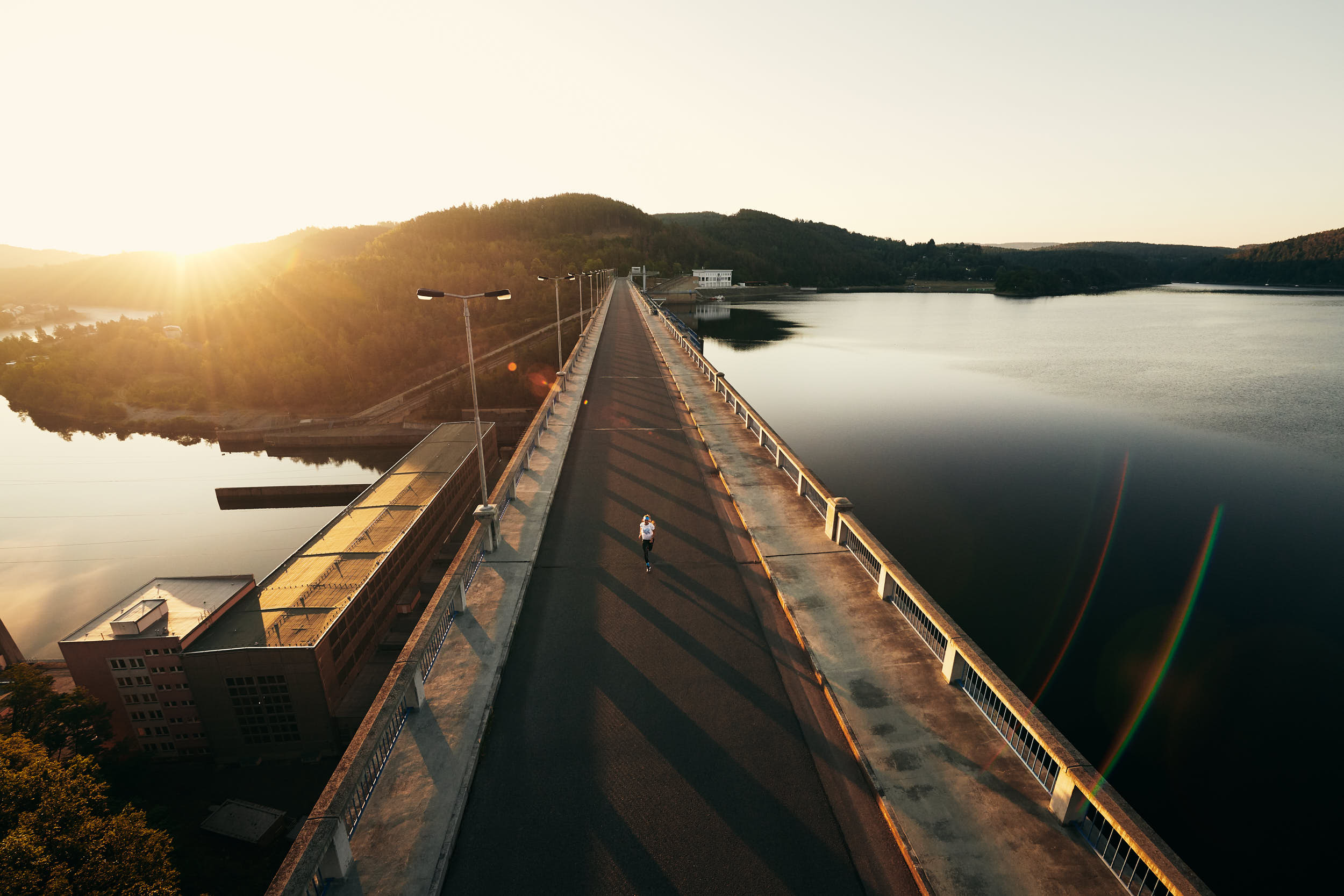 Sport advertising photography: girl running across a bridge in beautiful morning light.