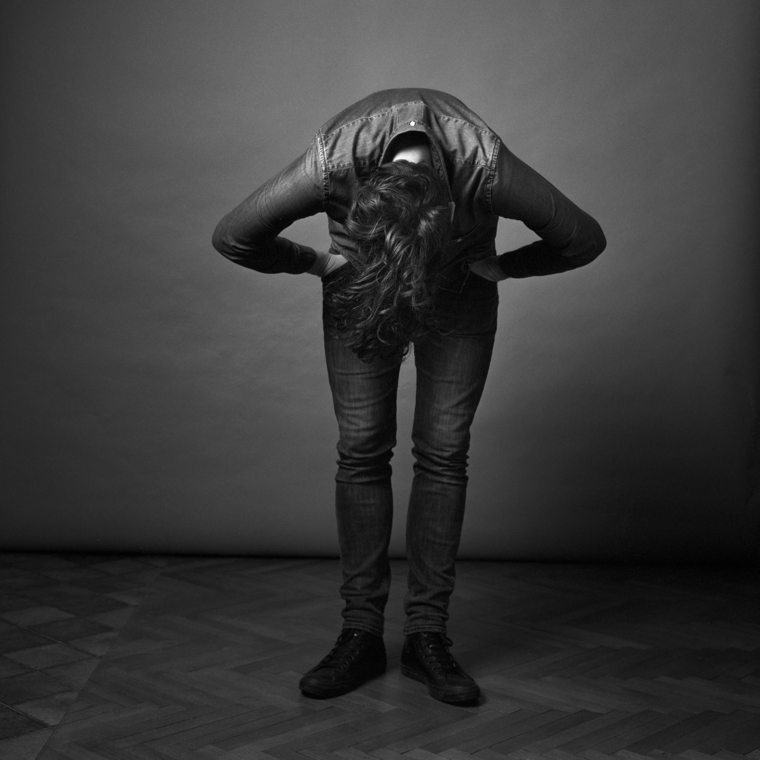 Black and white portrait photography: man with long hair leaning forward to adjust them.