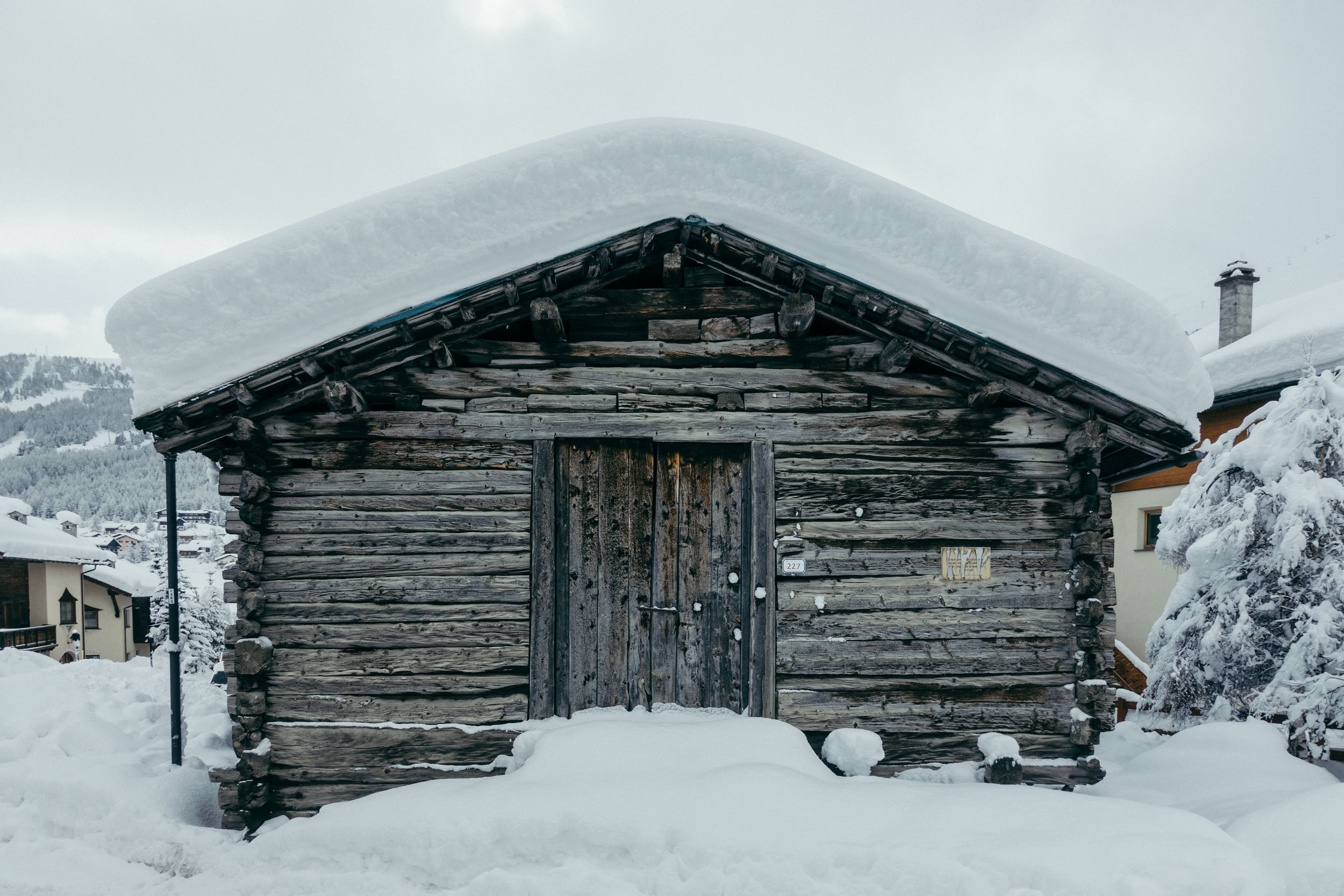 Old mountain hut with a big layer of snow on the roof.