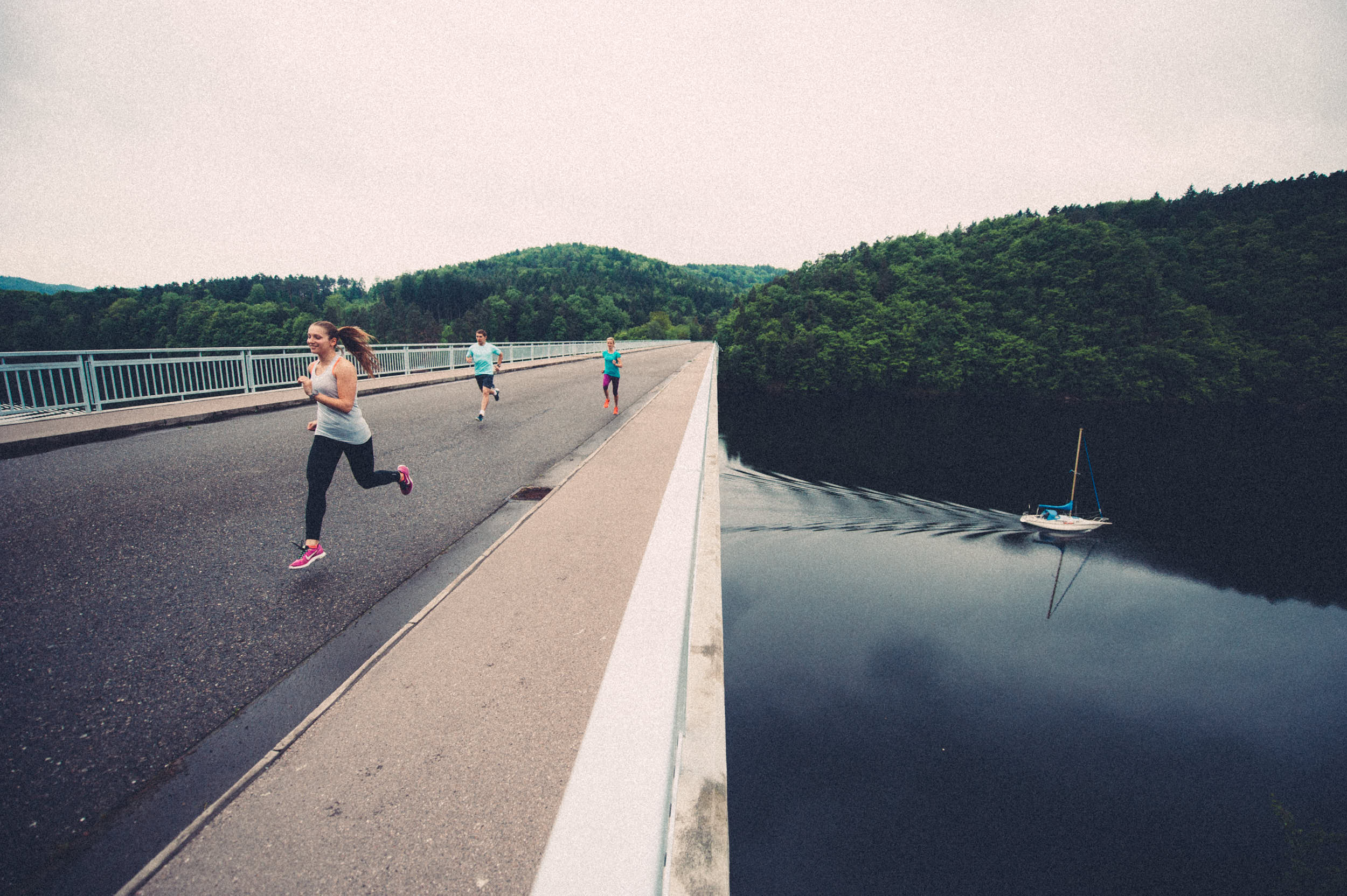 Group of athletes running across a bridge over a dam.