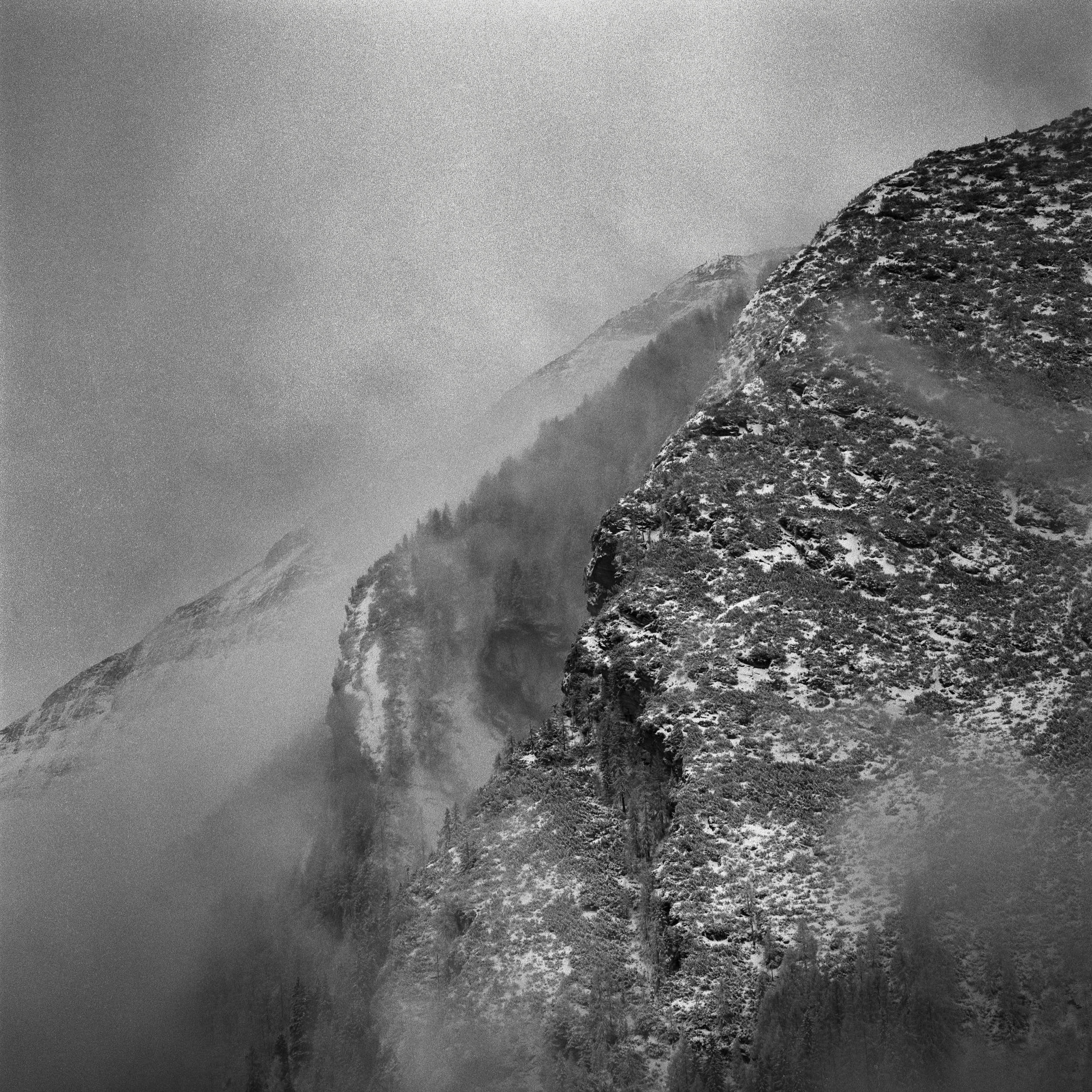 Black and white medium format film photography: detail of a steep mountain in fog.