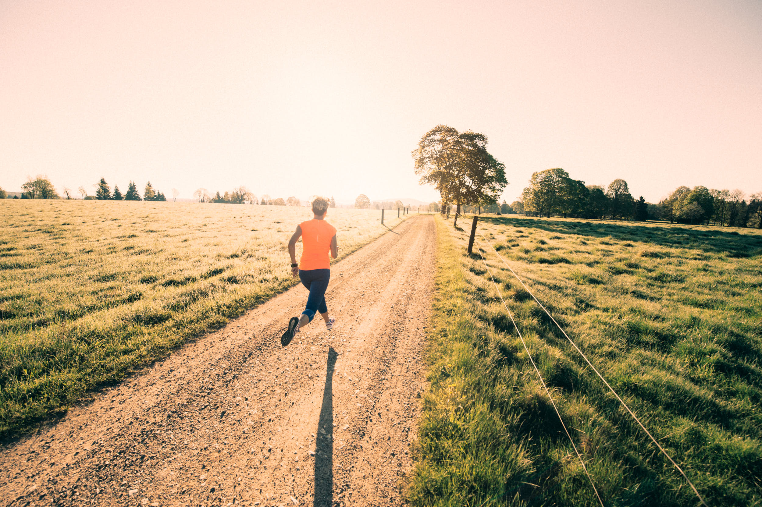 Girl running across a mountain meadow at dawn.