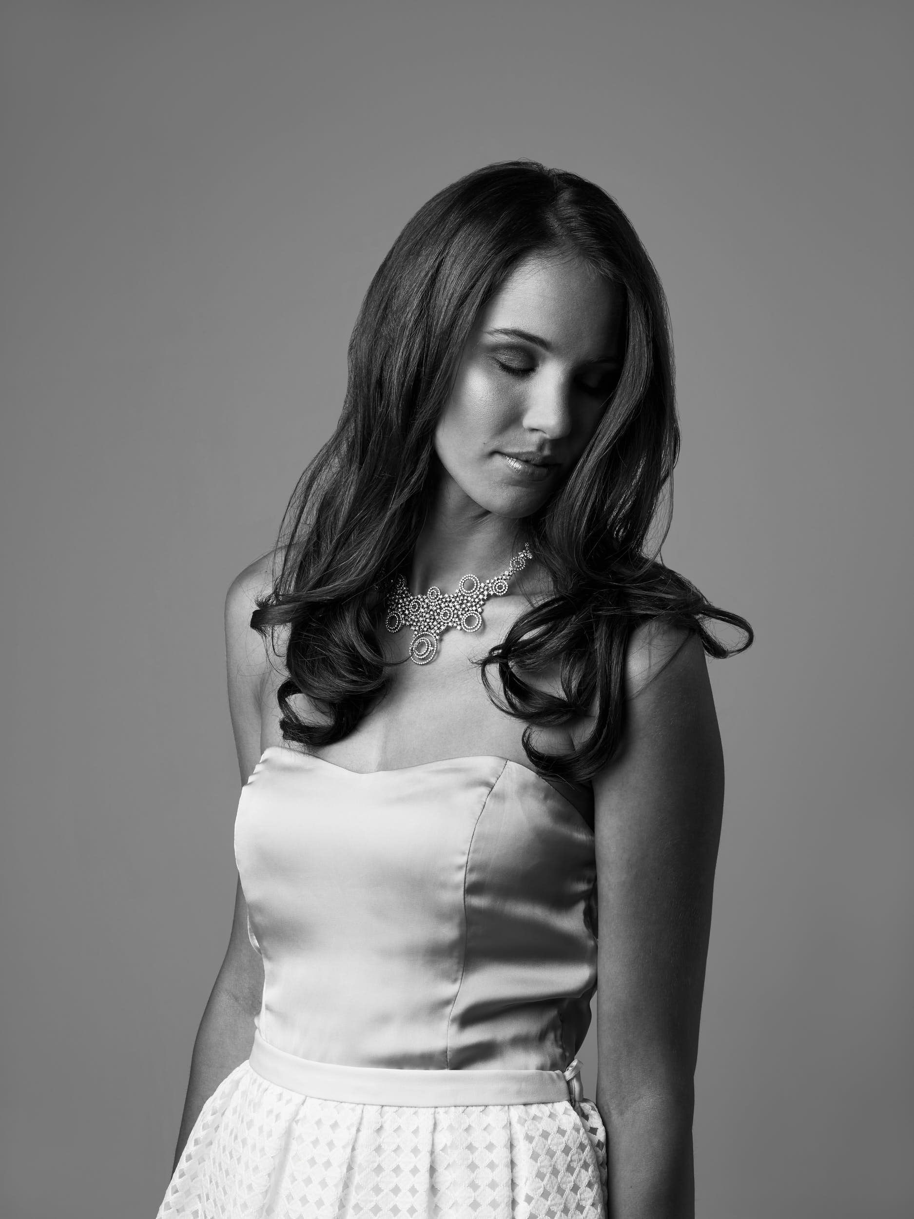 Black and white studio portrait of a woman wearing diamond necklace.