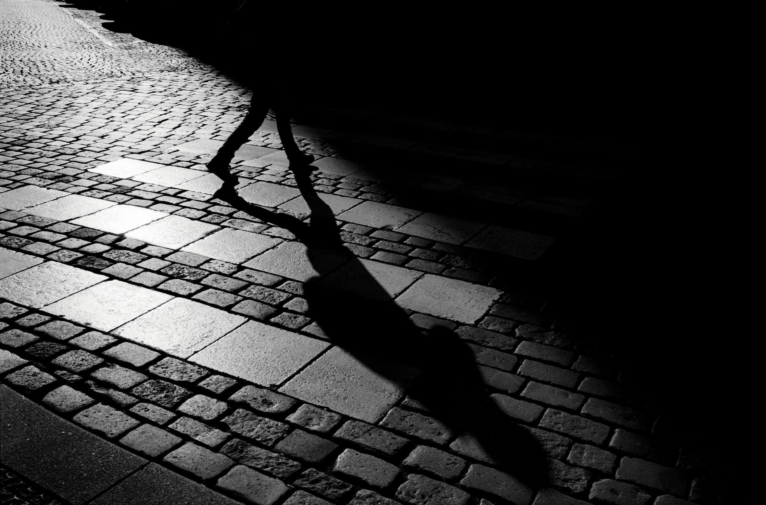 High contrast film street photography: man on a pedestrian crossing with deep shadows and geometric composition.
