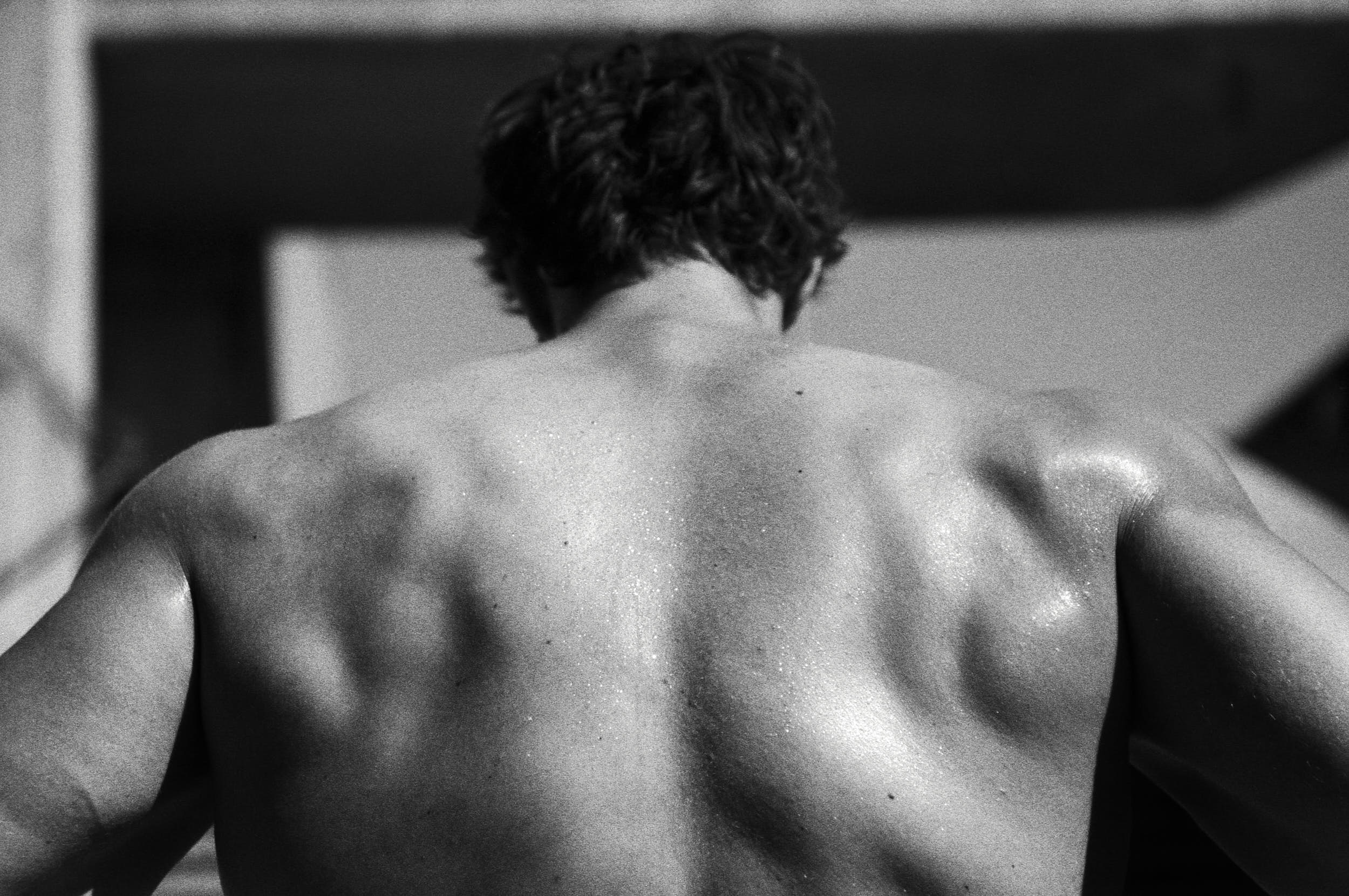 Muscular back of a fitness athlete in a black and white sport advertising photography.