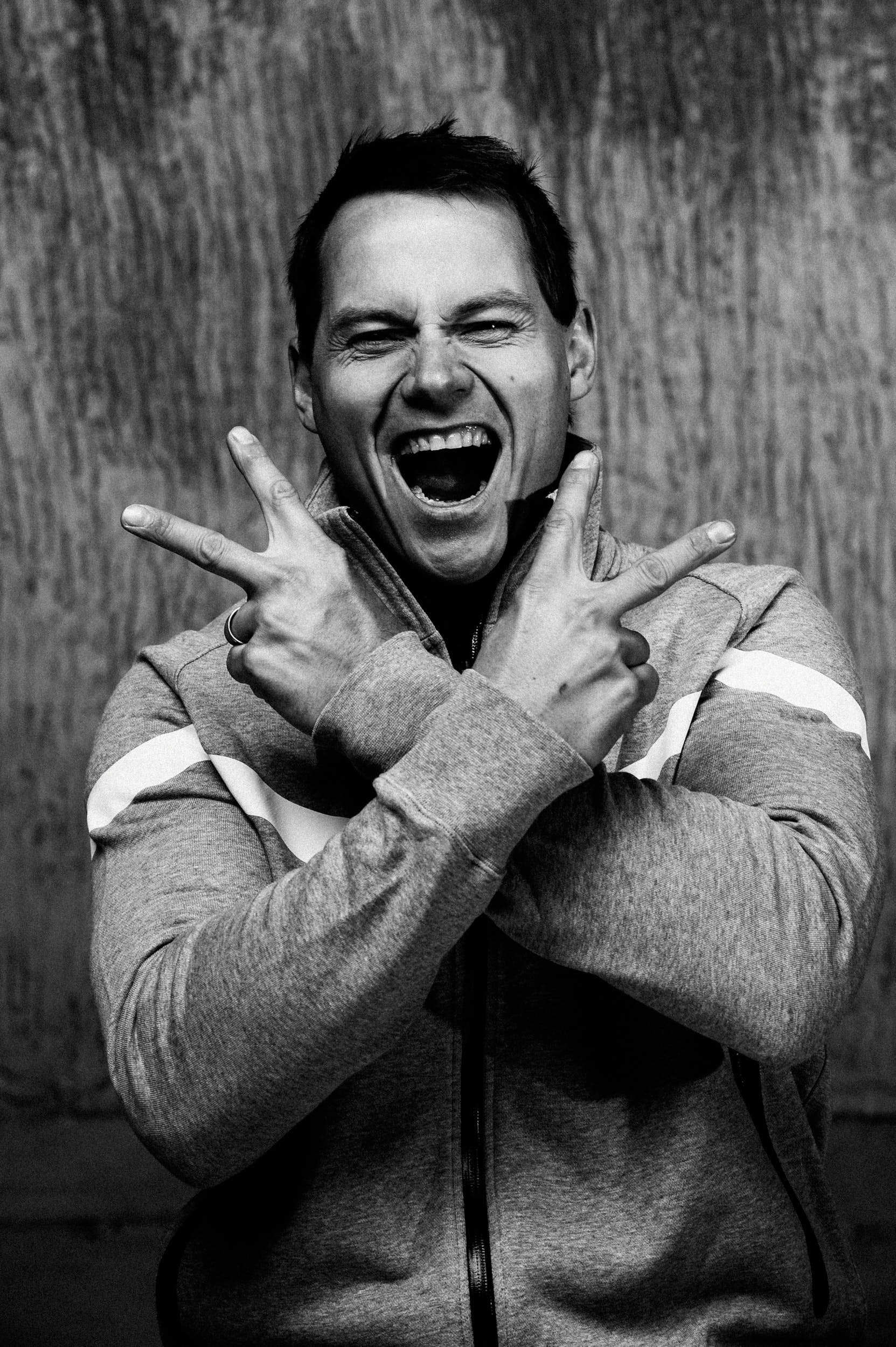 Black and white portrait of an athlete screaming and making the victory gesture with his hands.