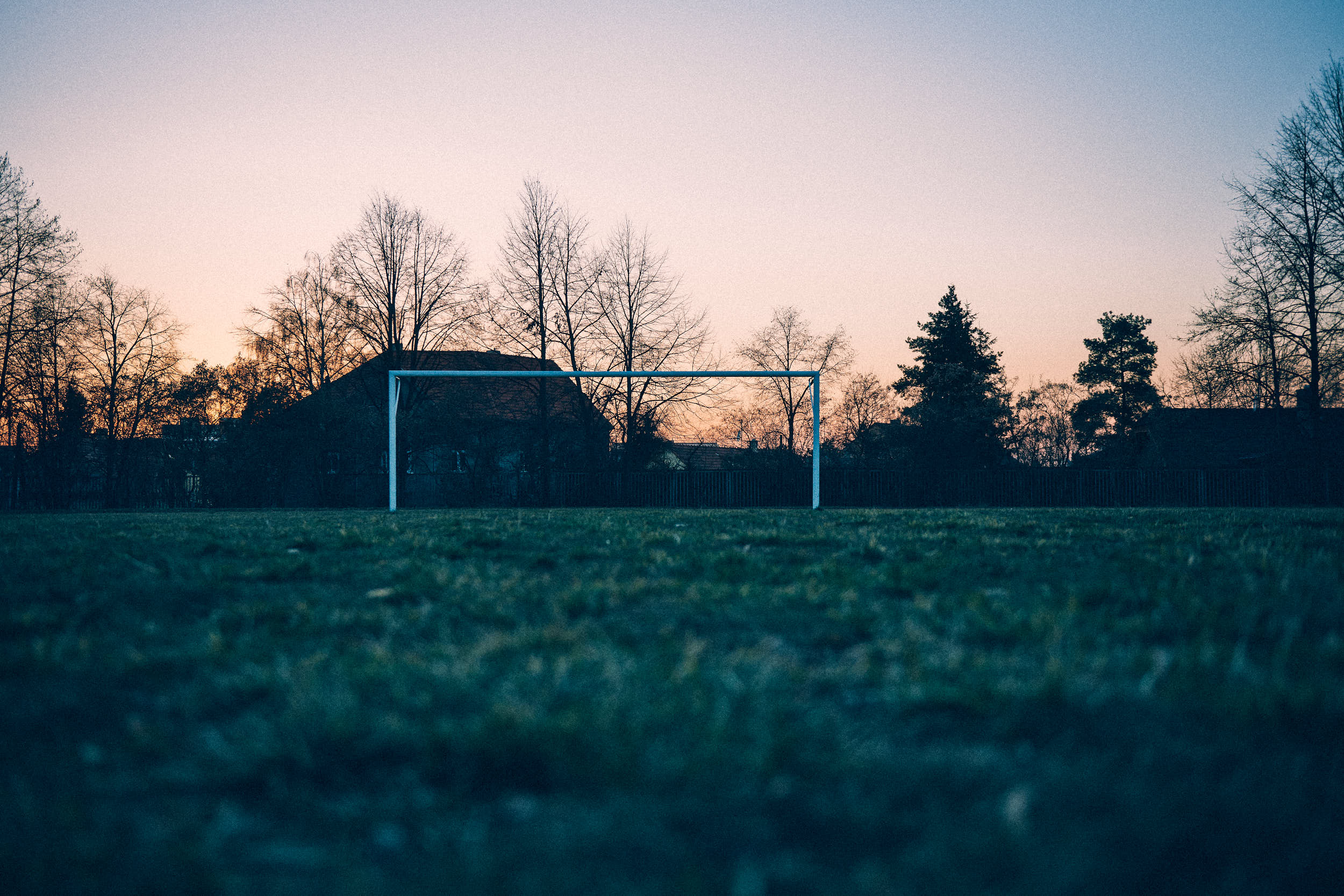 Abandoned football pitch with white goal at dusk.
