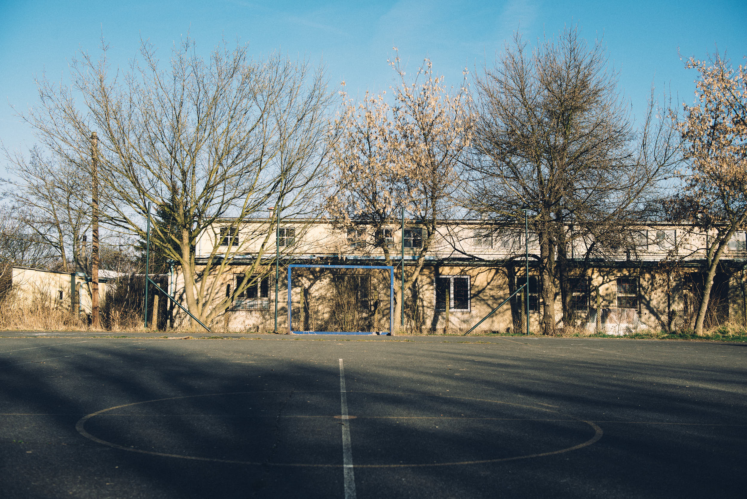 Abandoned blue goal on a concrete court.