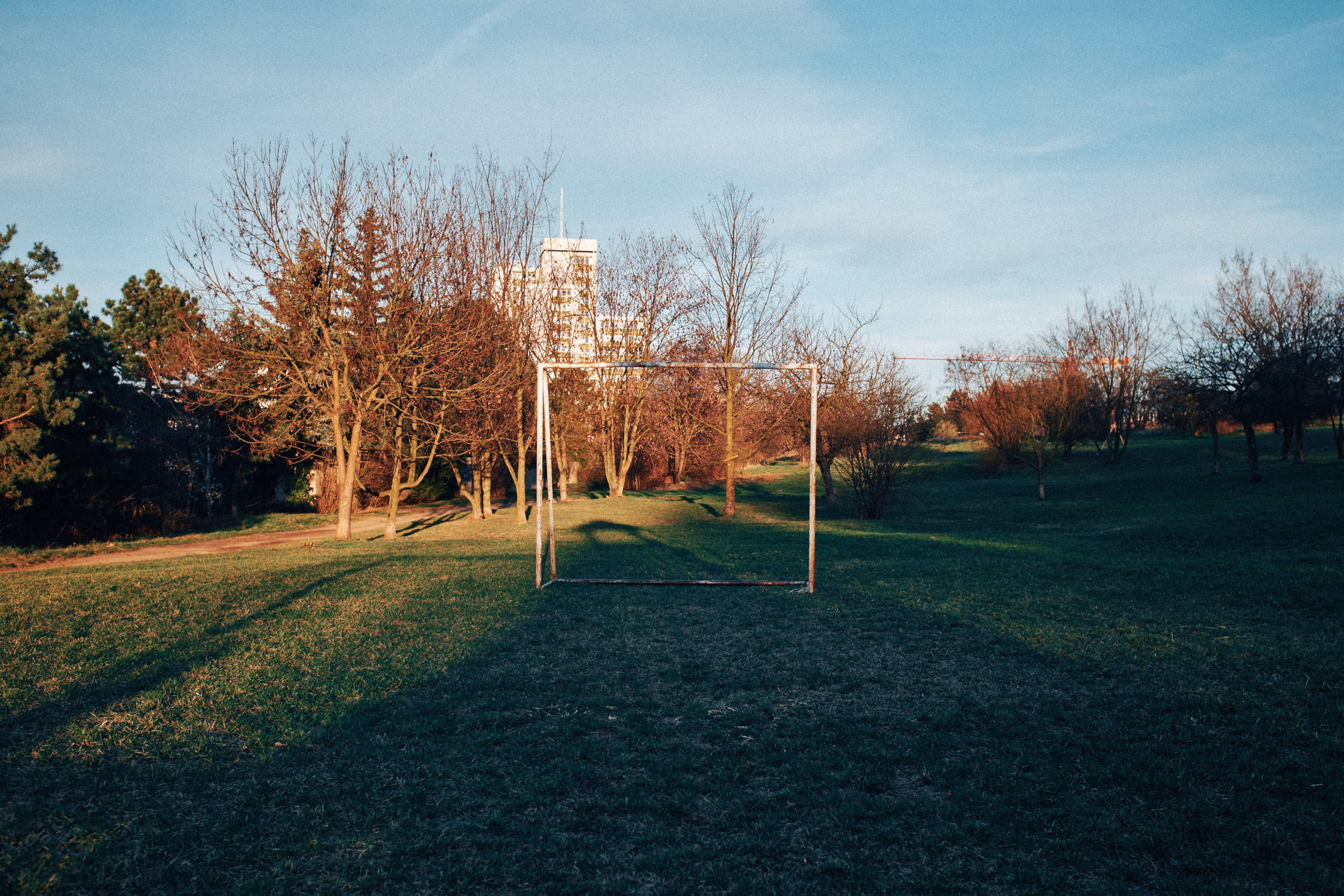 Abandoned football goal in a city park during golden hour.