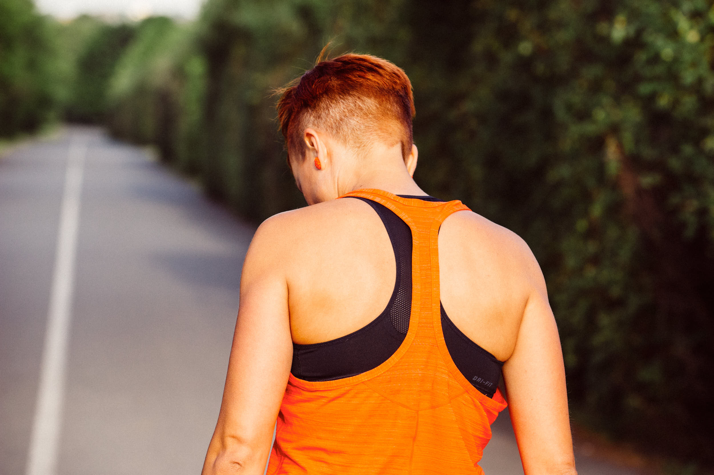 A girl with orange hair and tank top is preparing herself for a run.