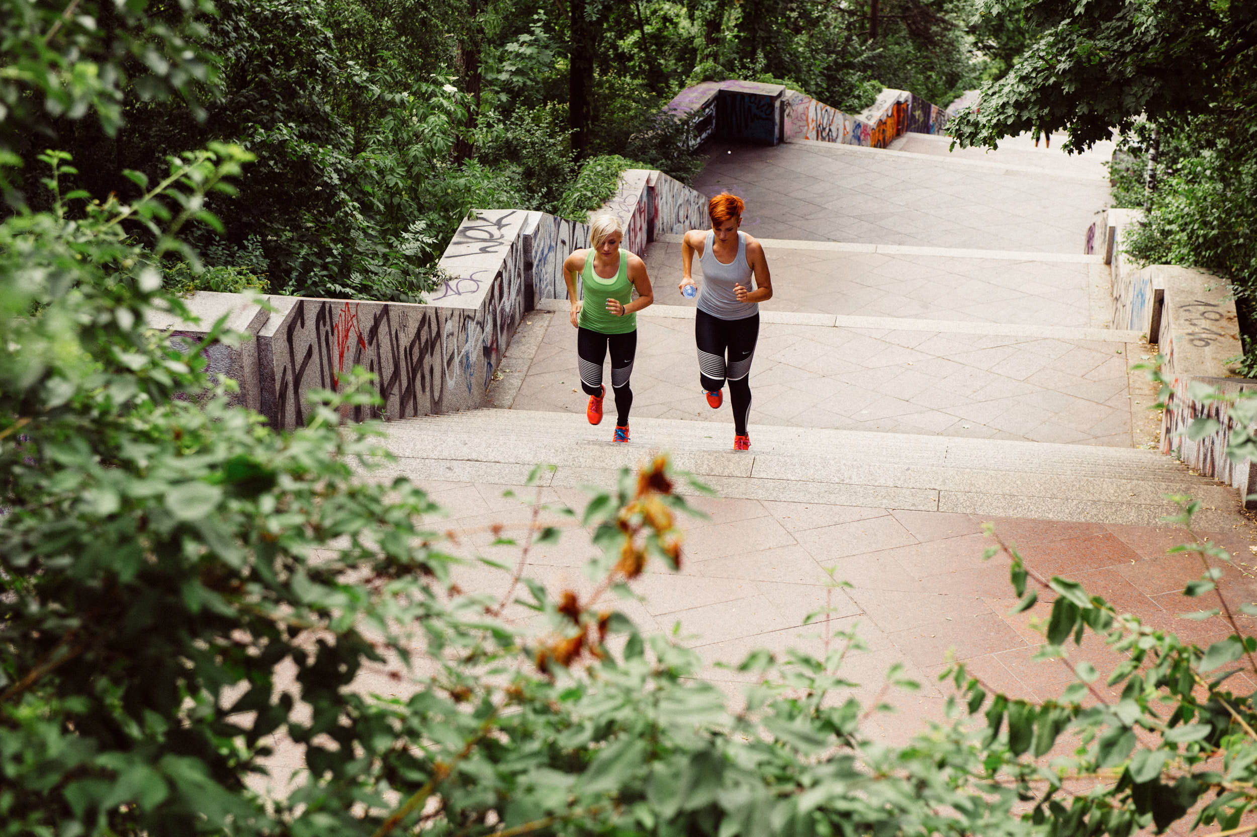 Active lifestyle photography: two girls running up a staircase in a city park.