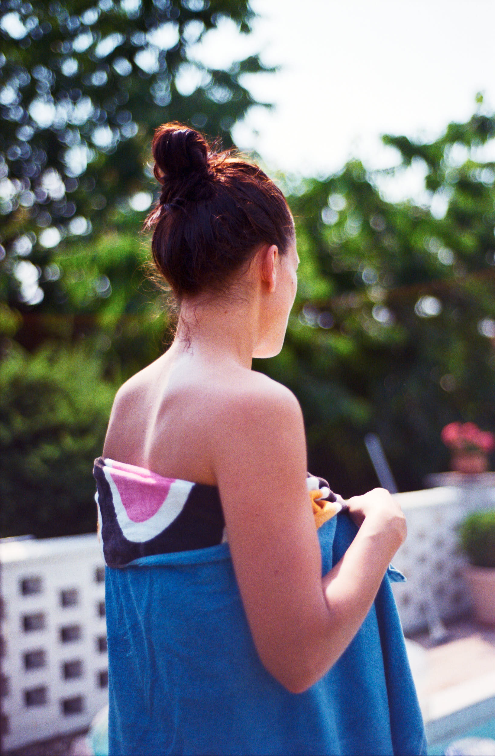 A girl standing by the pool with towel wrapped around her body.