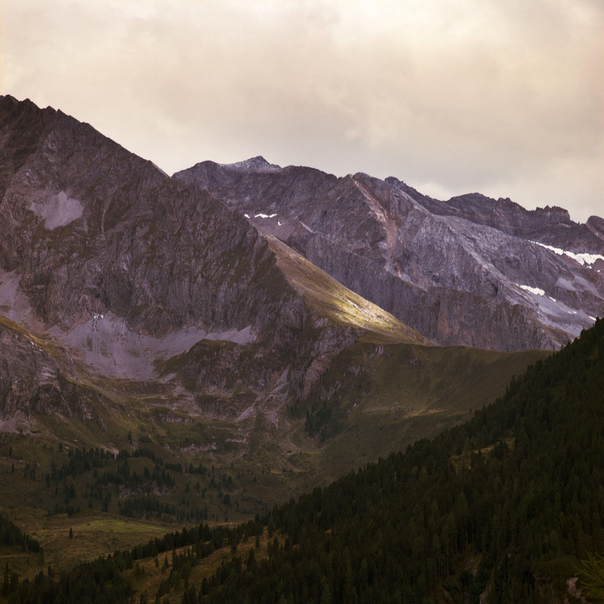 Film landscape photography: beautiful alpine peaks with spots of sunlight.