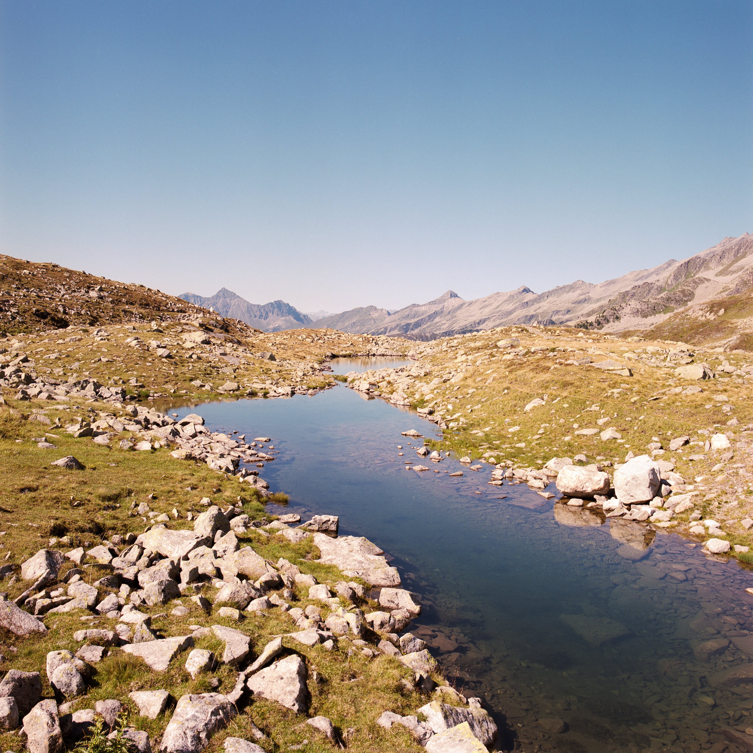 Colour film landscape photography: mountain stream with big rocks on an alpine mountainside.