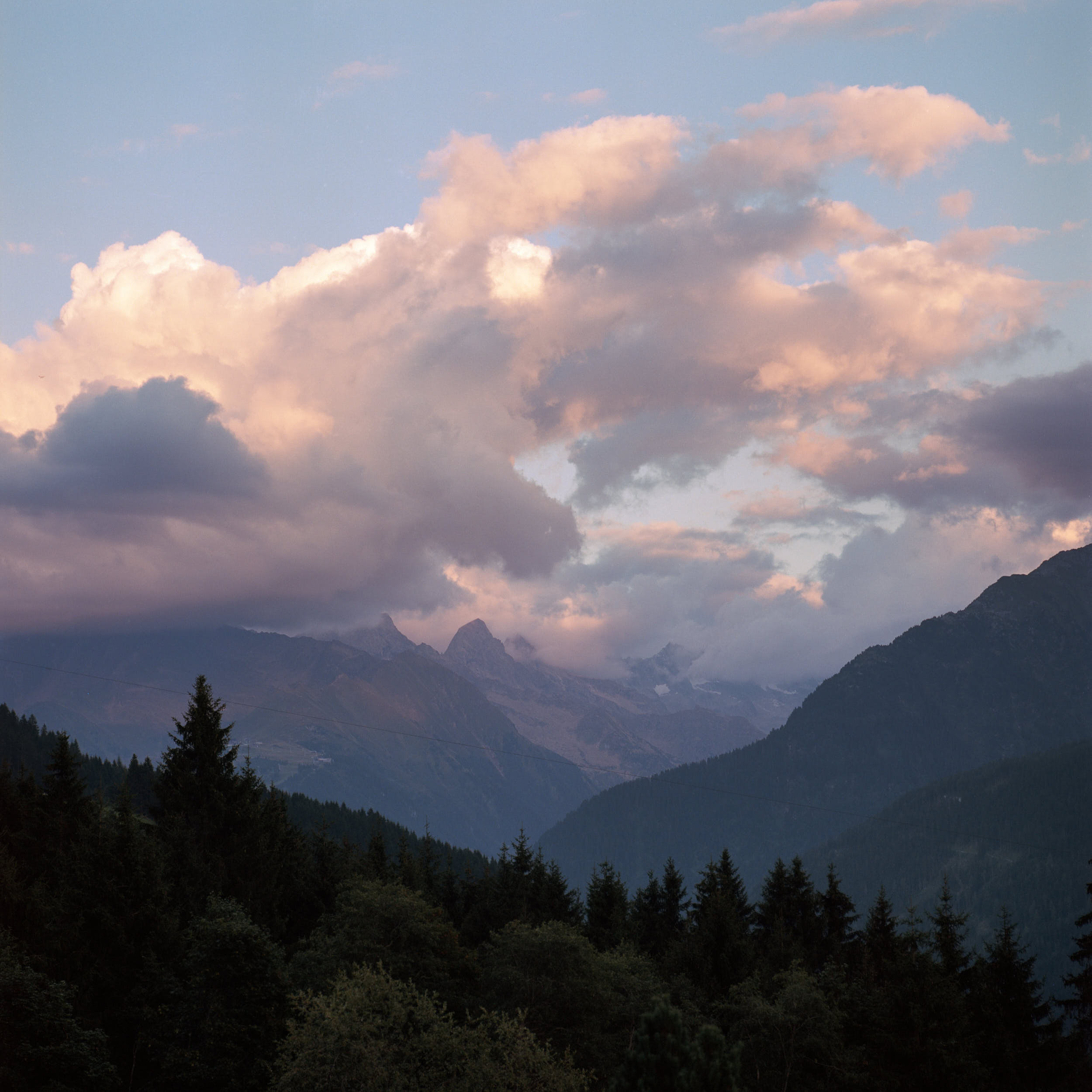 Last sun hitting high alpine peaks with dramatic sky.