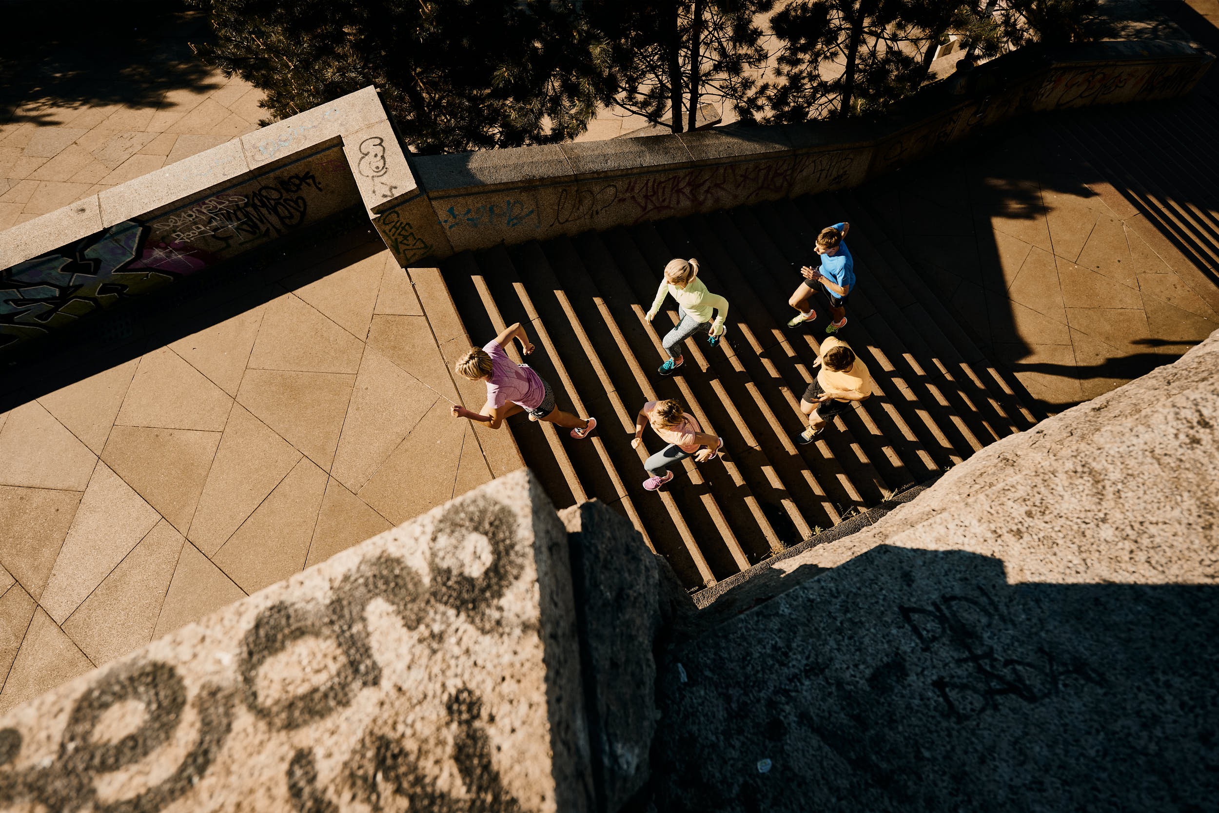 Running campaign photography: group of athletes running up a staircase shot from above.