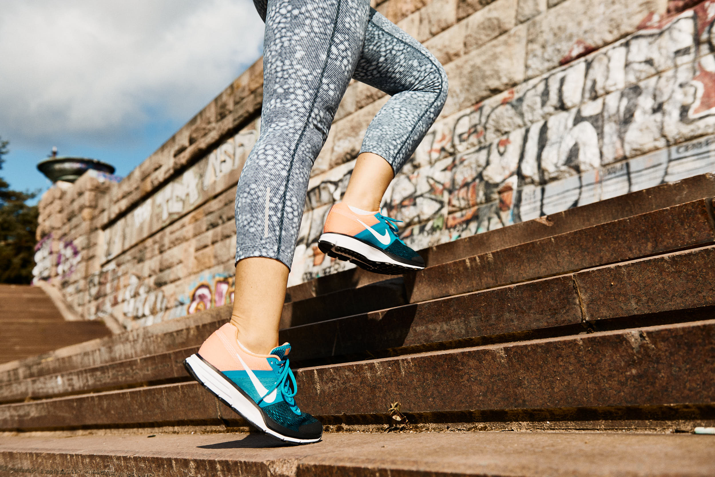 Running apparel advertising photography: detail of a girl in running shoes on stairs.