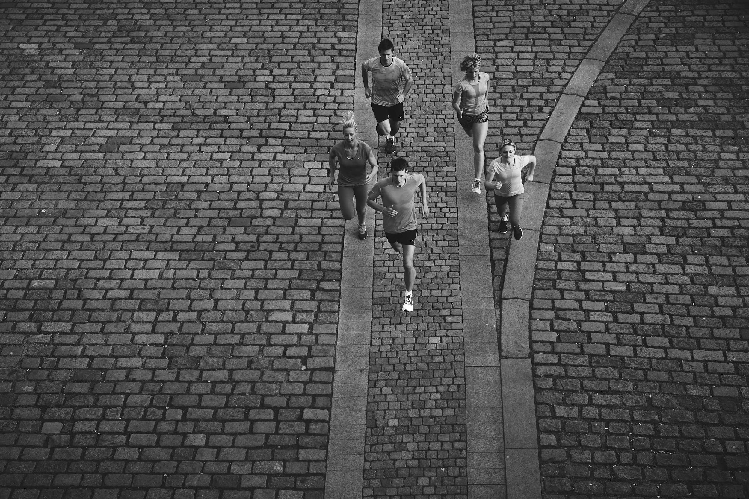 Black and white sports photography: group of runners on pavement photographed from elevated perspective.