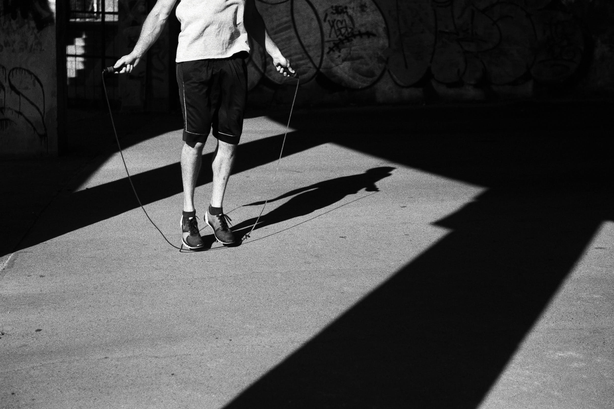 High contrast detail of a man working out with a jump rope.