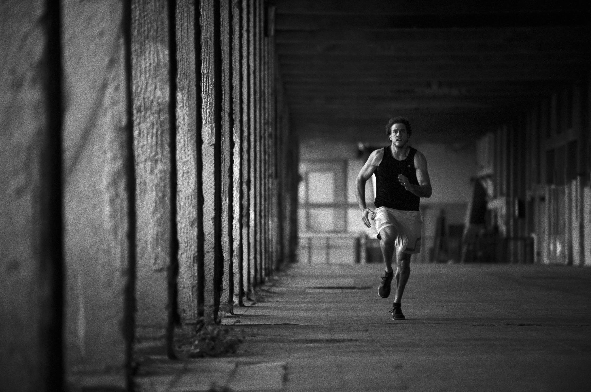 Muscular athlete sprinting in an industrial warehouse.