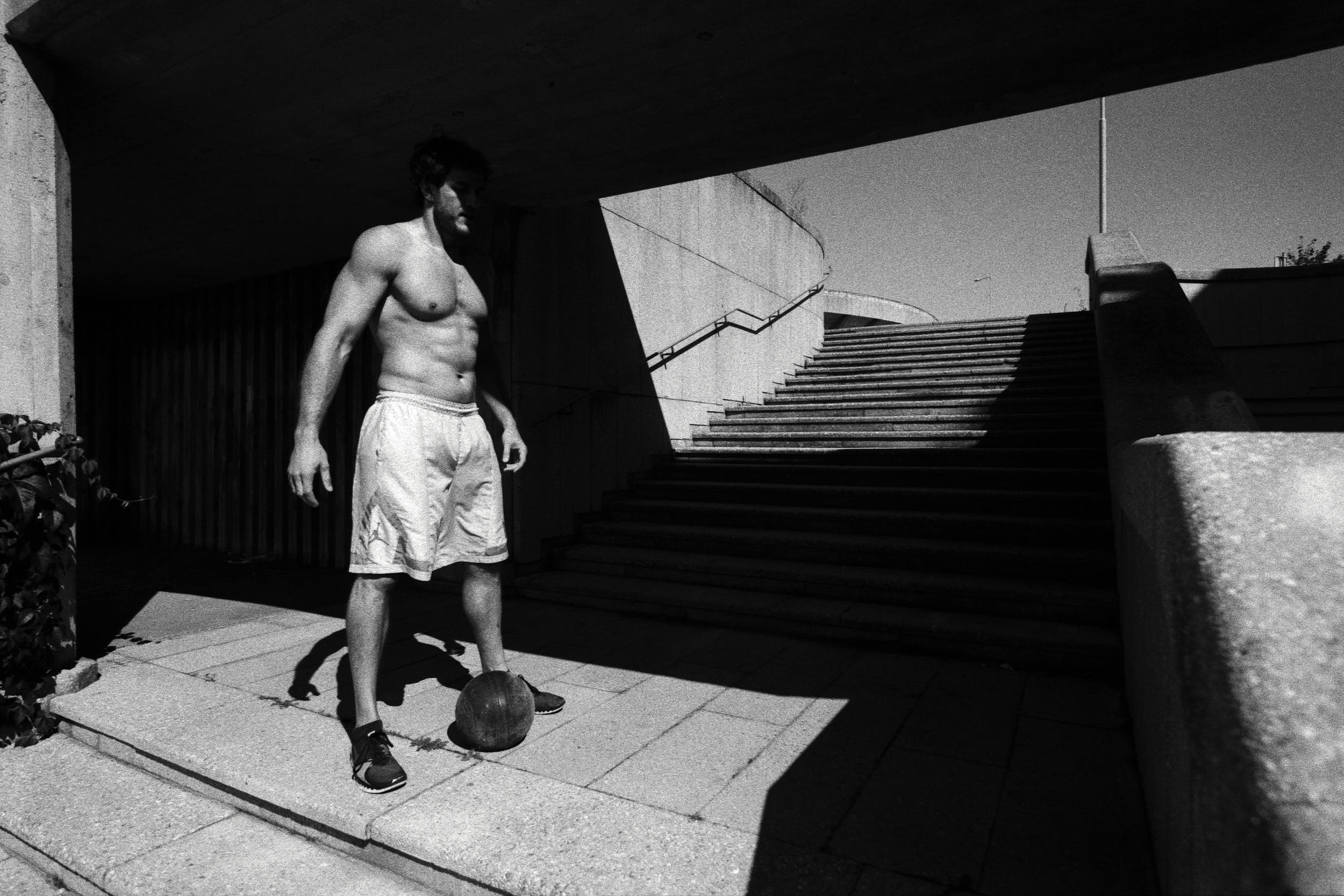 Crossfit athlete on a brutalist staircase preparing for a work out with a medicine ball.