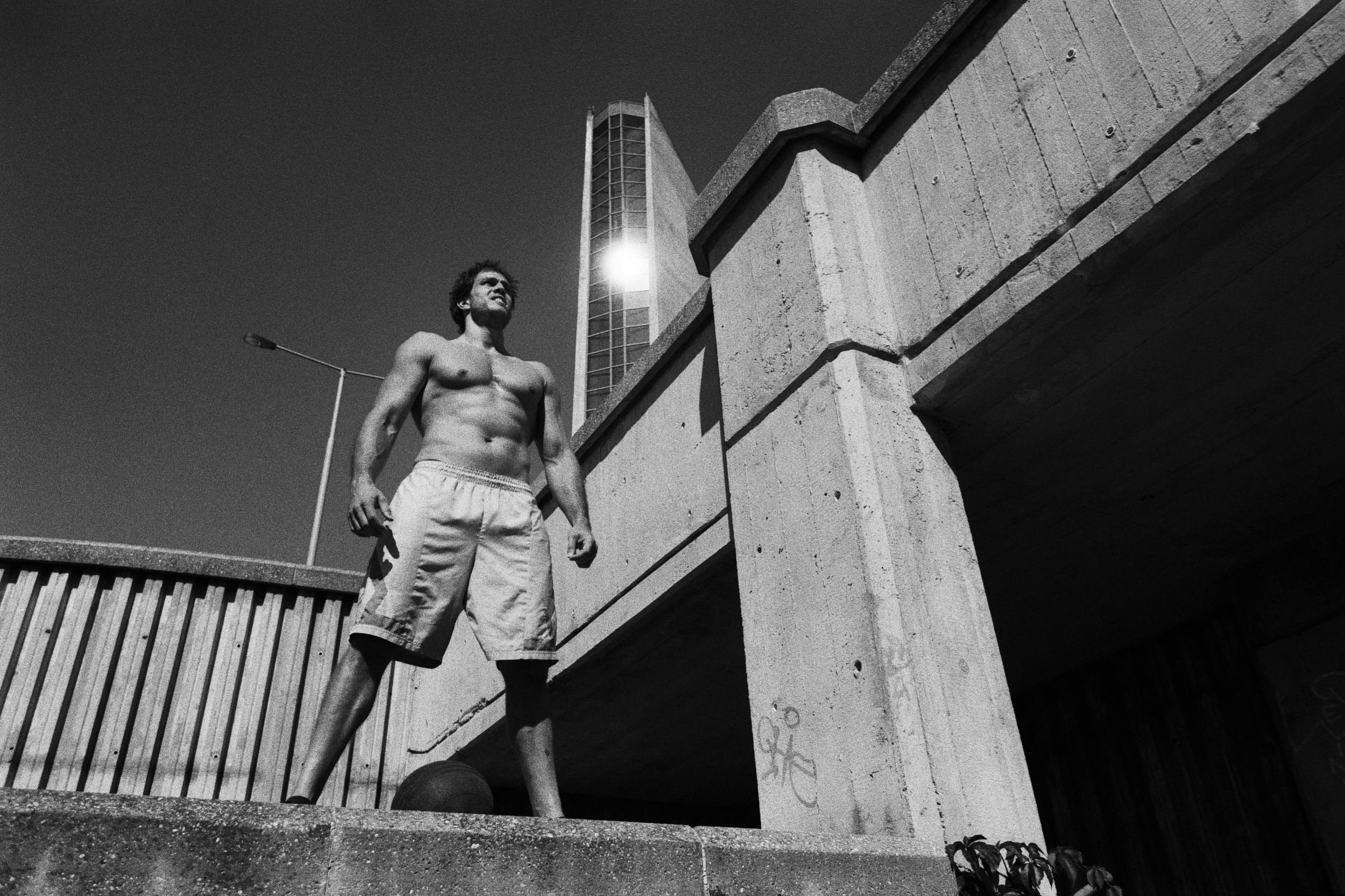 Crossfit athlete on a brutalist staircase preparing for a work out with a medicine ball.