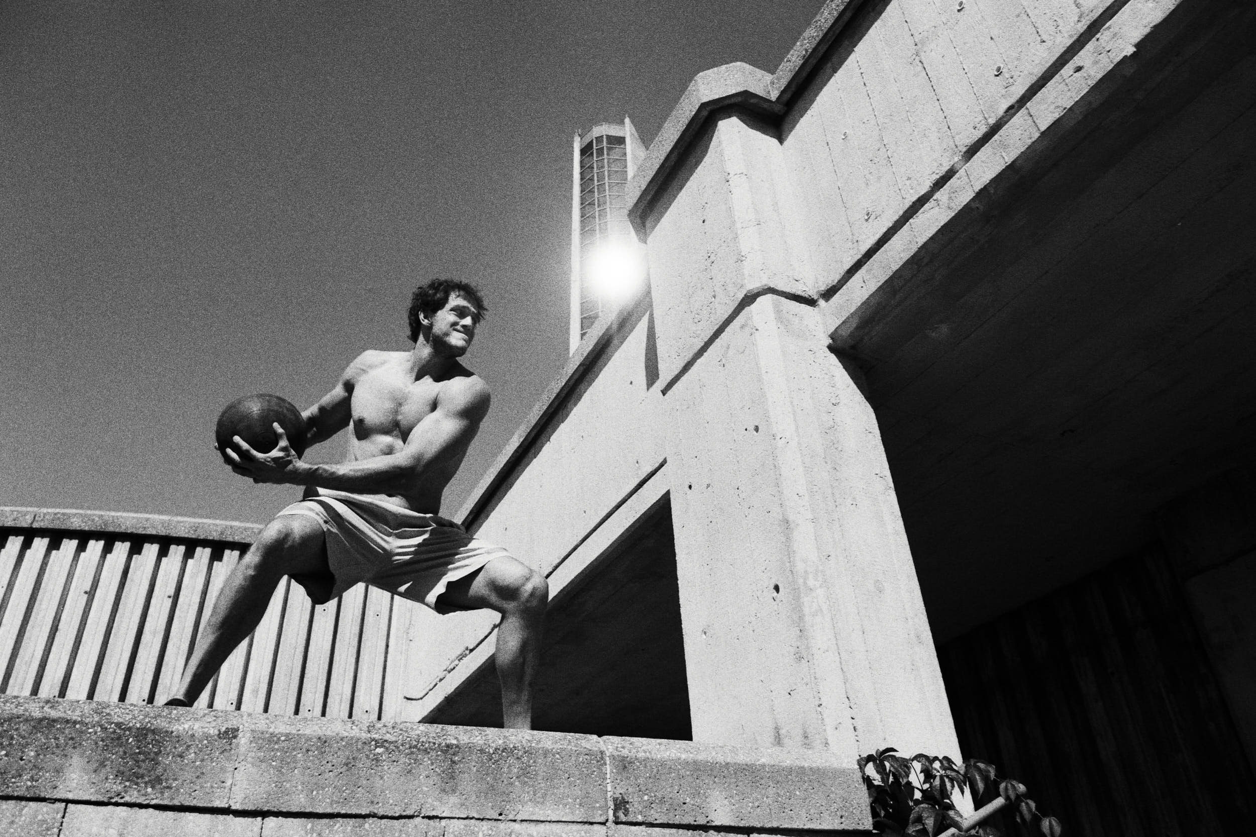 Action sports photography: Crossfit athlete on a brutalist staircase preparing for a work out with a medicine ball.