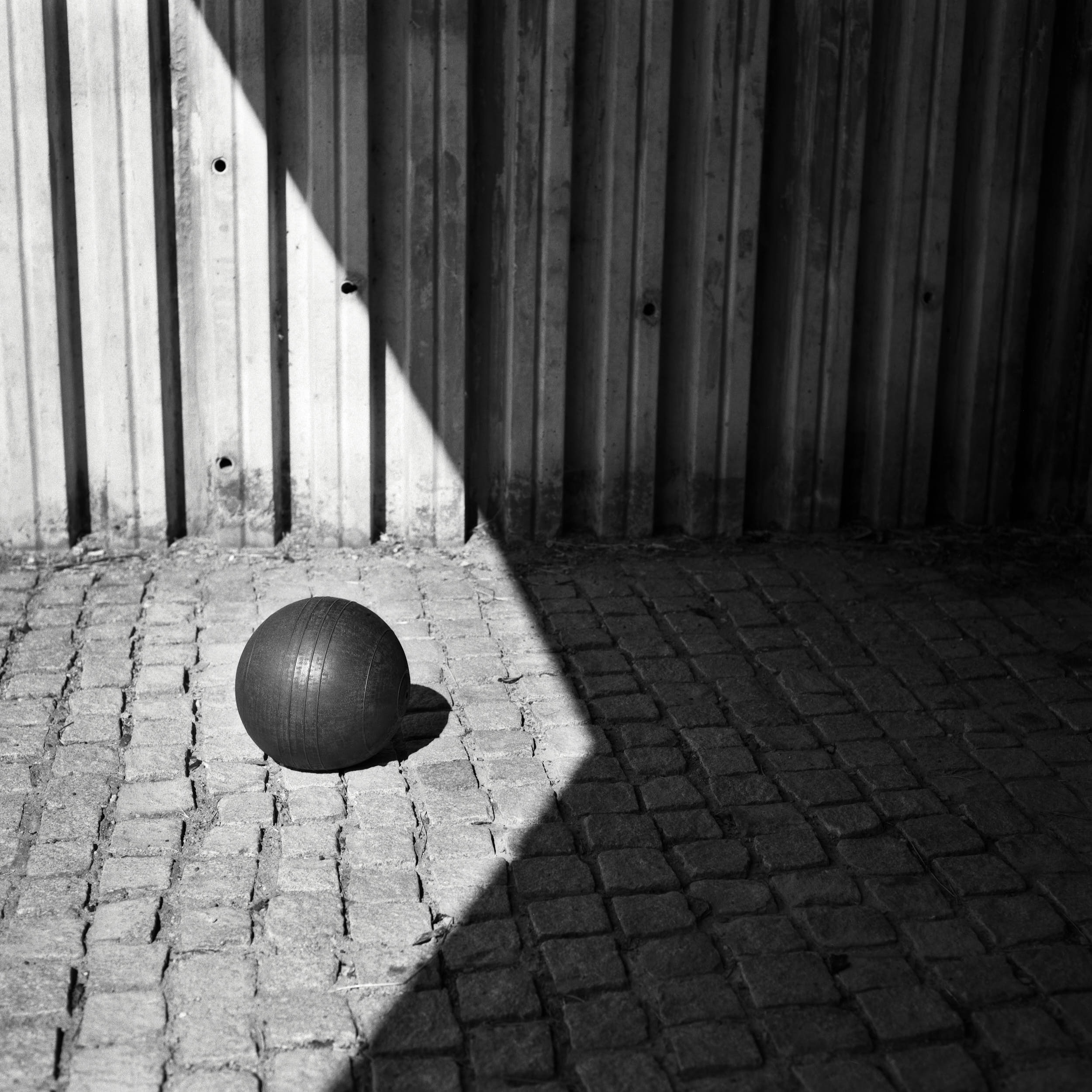 Sports still life photography: medicine ball in a geometric composition with deep shadows and high contrast.